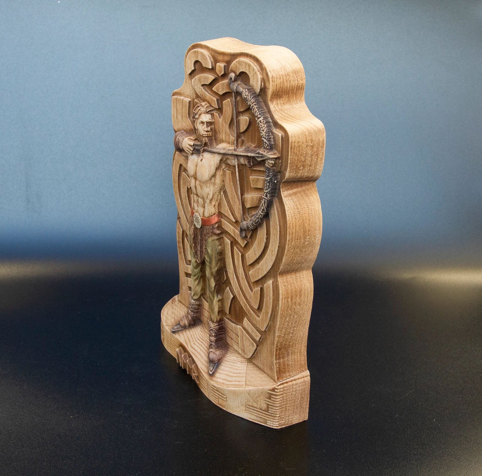 Angled side view of wooden Ullr figurine, Norse archer statue with carved bow and Celtic background on solid Viking wood base.